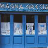 Nel quartiere Picone, in via Lembo, si trova infine la taverna Magna Grecia. Gi� dalla facciata notiamo i colori blu e bianco della bandiera greca, che dominano anche il piccolo locale